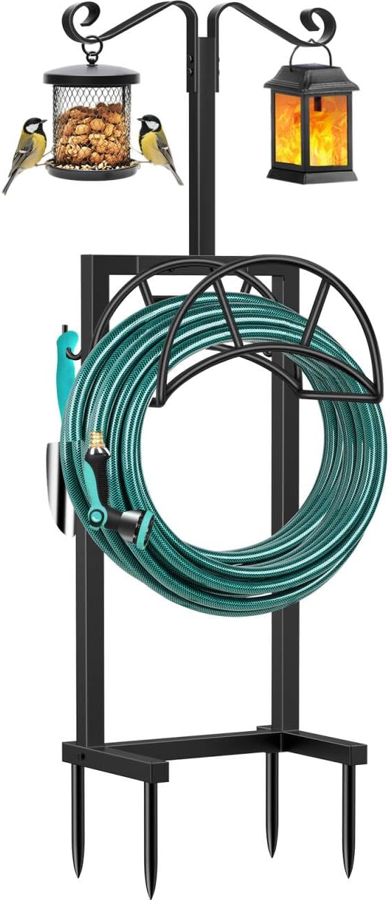 TomCare freestanding black steel garden hose stand with four ground spikes, a coiled green hose on the hoop and two hanger arms holding a bird feeder and a lantern